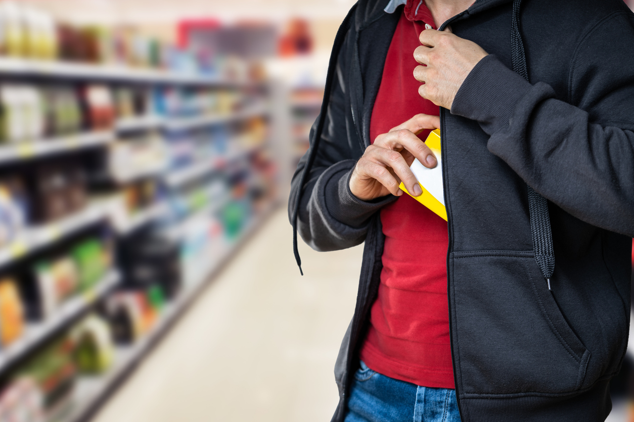 A person placing an item into his jacket at a store